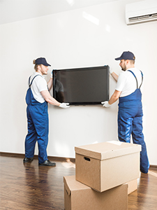 Movers hanging a television on the wall